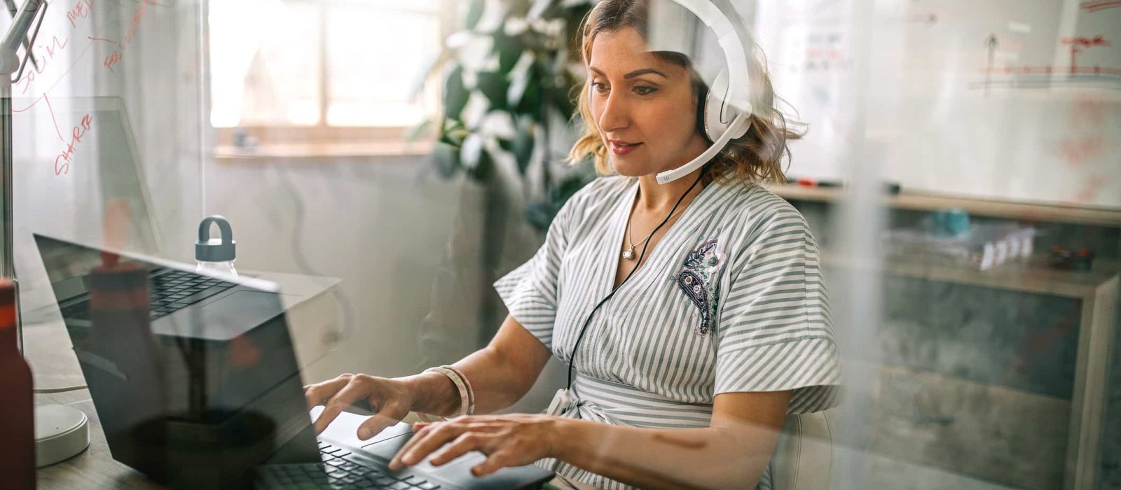 Businesswoman using laptop and headphones at office